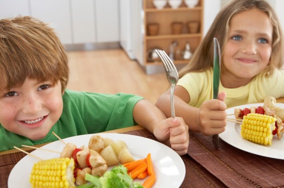 Un niño y una niña comiendo en la mesa